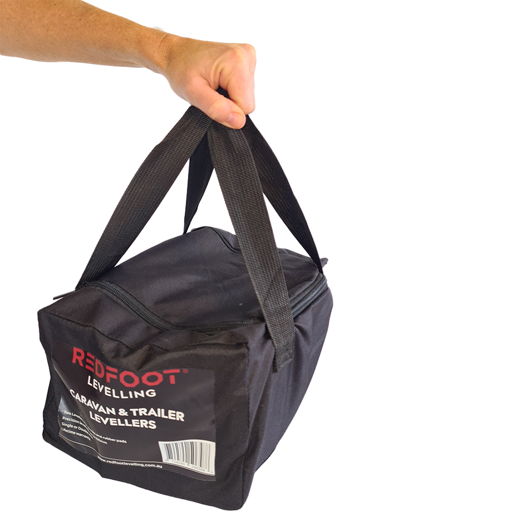 Redfoot Levelling - A person holding a black bag with the word "redfoot" on it, showcasing Redfoot Levelling Camper Levellers and chocks.